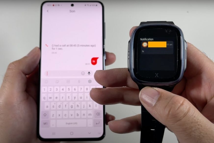 Man sieht die XPLORA X5 Play Kidswatch neben einem Handy. 